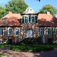 Fikensolt4.JPG Ein historische Backsteinherrenhaus mit symmetrischem Rotdach und gepflegtem Garten.