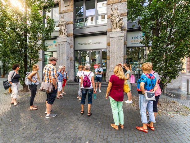 Un groupe de touristes se tient devant l'entrée de l'office de tourisme de Leipzig et reçoit une visite guidée, excursion, court séjour