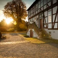 Ein Sonnenaufgang taucht die historische Fachwerkfassade des Mallinckrodthofs in warmes Licht.