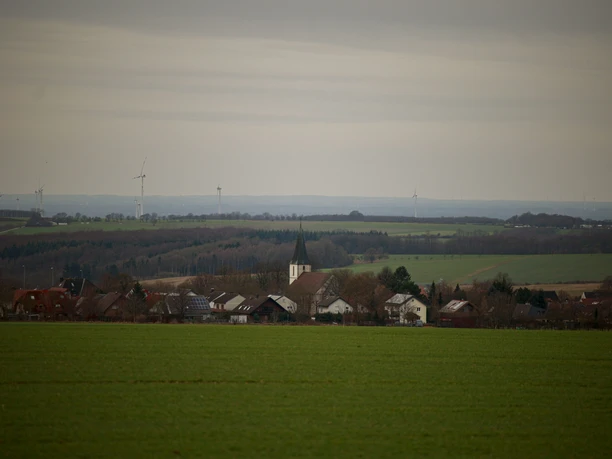 Dörenhagen Dorfansicht Dorfansicht von Dörenhagen mit Kirchturm im Zentrum, umgeben von sanften Hügeln und Windkraftanlagen.