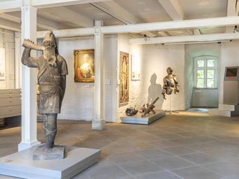 Ausstellung Stadtmuseum Wolfsburg Innenraum einer historischen Ausstellung mit Ritterrüstung, Gemälden und Holzskulptur im Museum.