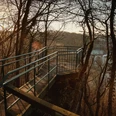 Aussichtspunkt Teufelsstein oberhalb des Paddelteiches Etteln Metallplattform mit seitlichen Geländern in einem Waldgebiet, bietet Blick auf einen See bei Sonnenuntergang.