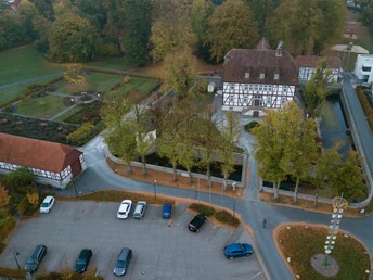 Luftaufnahme des historischen Mallinckrodthofs, umgeben von Bäumen, Gartenanlagen und Parkplätzen.