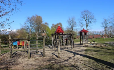 Spielplatz Cadenberge Holzspielplatz mit Klettergerüsten, Rutschen und Türmen im Grünen unter blauem Himmel in Cadenberge.