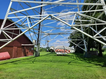 Metallkonstruktion des Deutschen Windkraftmuseums in sonniger, grüner Umgebung mit Nordex-Windrad.