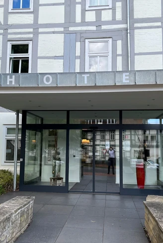 Eingang eines modernen Hotels mit breiten Zugängen, großen Glasflächen und gut sichtbarem Schriftzug.