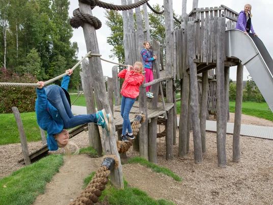 Klettern im Freizeitpark Nordstadt in Velbert Kinder spielen auf einem abenteuerlichen Holzklettergerüst mit Seilen und Rutsche im Freizeitpark.