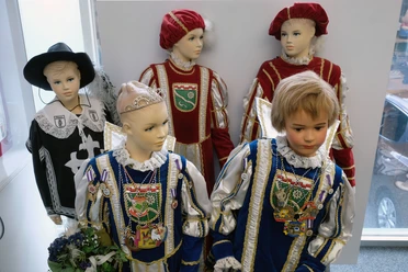 Rheinisches Karnevalsmuseum Fünf Schaufensterpuppen präsentieren mittelalterliche Karnevalskostüme mit aufwendiger Verzierung.