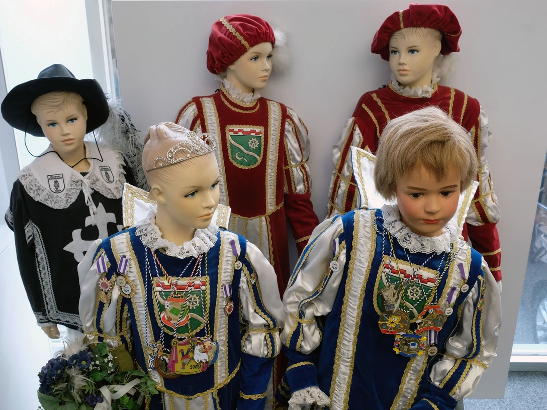 Rheinisches Karnevalsmuseum Fünf Schaufensterpuppen präsentieren mittelalterliche Karnevalskostüme mit aufwendiger Verzierung.