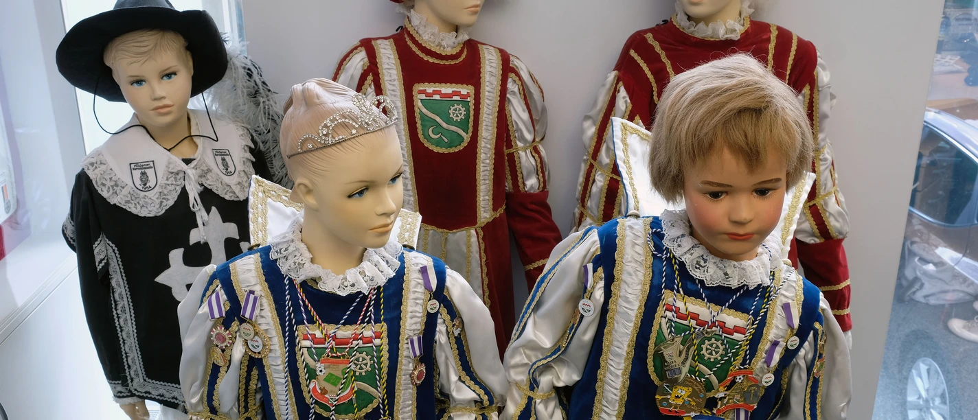 Rheinisches Karnevalsmuseum Fünf Schaufensterpuppen präsentieren mittelalterliche Karnevalskostüme mit aufwendiger Verzierung.