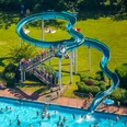 Heljensbad in Heiligenhaus Ein Freibad mit einer geschwungenen blauen Wasserrutsche, umgeben von einer grünen Liegewiese.