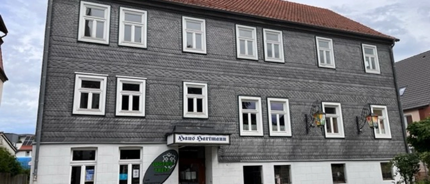 Das graue Fachwerkhaus mit weißen Fensterrahmen beherbergt das Heimatmuseum. Pflastersteinweg vorne.