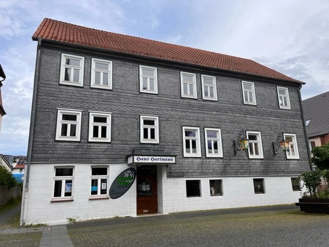 Das graue Fachwerkhaus mit weißen Fensterrahmen beherbergt das Heimatmuseum. Pflastersteinweg vorne.