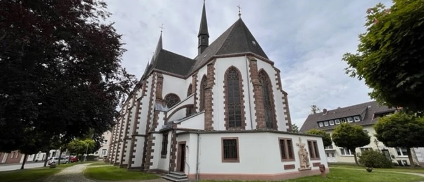 Martinskirche mit markanten gotischen Bögen und Türmen, umgeben von gepflegtem Grün und Wegen.