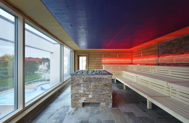 Große Saunalandschaft in der carpesol SPA Therme Modern sauna with panoramic windows, wooden benches and atmospheric LED lighting.