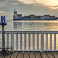 Cuxland, Cuxhaven - Alte Liebe Ein Containerschiff fährt bei Sonnenuntergang vor einer blauen Aussichtsplattform auf dem Wasser.A container ship sails in front of a blue viewing platform on the water at sunset.Et containerskib sejler foran en blå udsigtsplatform på vandet ved solnedgang.Een containerschip vaart voor een blauw uitkijkplatform op het water bij zonsondergang.