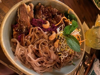 Bowl mit Ente Bowl mit knuspriger Ente, Reisnudeln, Sprossen, Cashews und frischen Kräutern, appetitlich angerichtet.