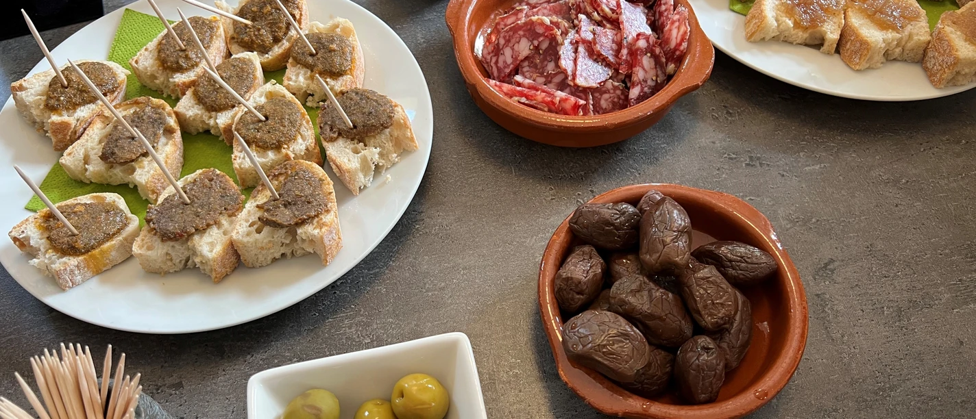 A variety of Italian starters on a table, including olives, sausage and slices of bread.