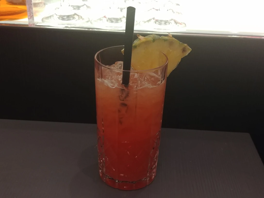 Cocktail Ein bunt geschichteter Cocktail in einem Kristallglas, dekoriert mit Ananasstück und schwarzem Strohhalm.A colorfully layered cocktail in a crystal glass, decorated with pineapple chunks and a black straw.En farverig lagdelt cocktail i et krystalglas, dekoreret med ananasstykker og et sort sugerør.Een kleurrijk gelaagde cocktail in een kristallen glas, versierd met stukjes ananas en een zwart rietje.