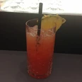 Cocktail Ein bunt geschichteter Cocktail in einem Kristallglas, dekoriert mit Ananasstück und schwarzem Strohhalm.