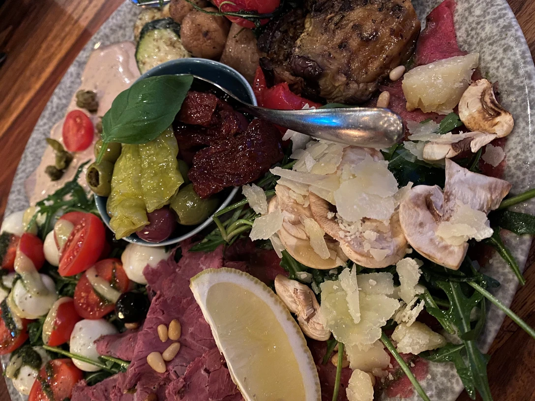 Antipasti Ein reichhaltiger Teller mit verschiedenen Antipasti: Mozzarella-Tomaten-Spieße, Paprika, Oliven und Rindfleisch.