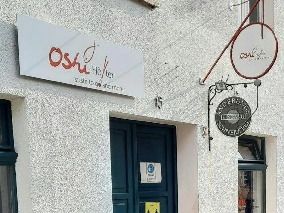 Eingang vom Restaurant Oshi mit Schild über der Tür