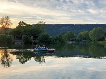 Tretboot mit Menschen auf dem See bei abendlichen Lichtverhältnissen