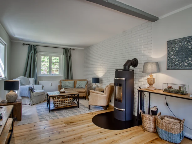 Wohnzimmer mit Holzboden Helles Wohnzimmer mit Holzboden, schwarzem Kamin, Sofa und TV vor weißer Wand.