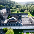 Jugendbildungsstätte Haus Altenberg Luftaufnahme der Abtei Mariawald inmitten grüner Landschaft, umgeben von Wäldern und Hügeln.