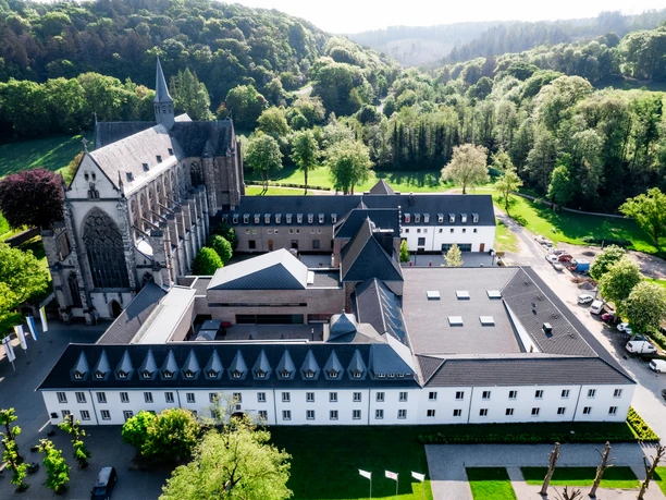 Jugendbildungsstätte Haus Altenberg Luftaufnahme der Abtei Mariawald inmitten grüner Landschaft, umgeben von Wäldern und Hügeln.