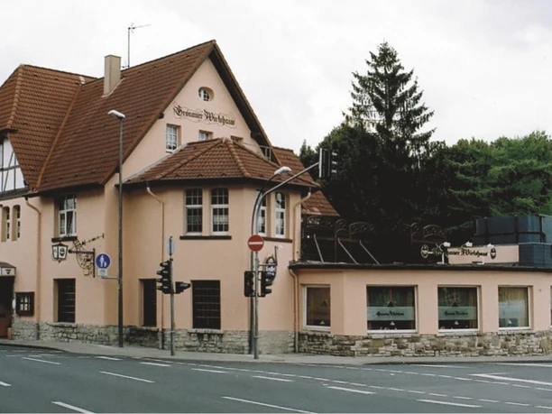 Außenansicht Historisches Gebäude mit roten Dachziegeln und Fachwerk, umgeben von Bäumen und Straße.