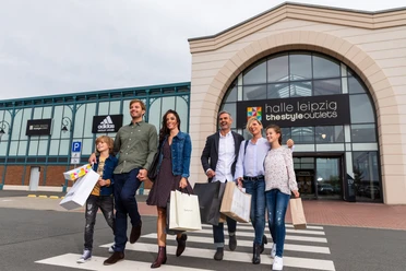 Une famille quitte le Halle Leipzig The Style Outlets Center en riant et en tenant des sacs de courses à la main, shopping, loisirs, famille, excursion