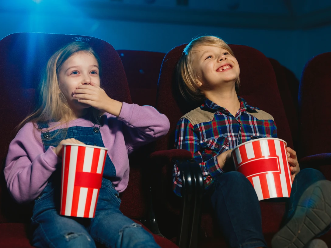 Little girl and boy, friends or sister and brother watching a film at a movie theater, house or cinema. Look expressive and emotional. Sitting alone and having fun. Friendship, family, childhood, weekend. Little girl and boy, friends or sister and brother watching a film at a movie theater, house or cinema. Look expressive and emotional. Sitting alone and having fun. Friendship, family, childhood, weekend.
