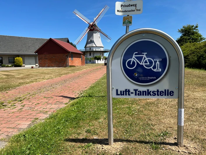 Lufttankstelle Behlmer Mühle Lufttankstelle für Fahrräder vor der historischen Behlmer Mühle mit weißen Flügeln und rotem Dach.