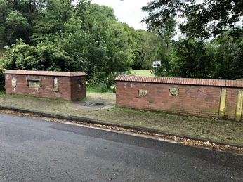 Sedanbrücke Die historische Sedanbrücke in einer grünen Umgebung, flankiert von Ziegelmauern mit Wappen.