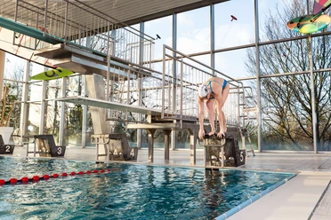 Hallenbad Angerbad in Ratingen Moderne Schwimmhalle mit Sprunganlage und großem Fenster, das viel natürliches Licht einlässt.