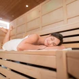 Sauna Lintorf in Ratingen Entspannende Sauna mit hölzernen Bänken, einer Person, die ruht und angenehmes Licht.