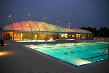 Allwetterbad Lintorf in Ratingen Beleuchtetes Allwetterbad Lintorf in Ratingen, Außenansicht bei Abenddämmerung mit Pool und Pavillon.