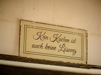 Café am Schloss, Dorsten Kein Kuchen ist auch keine Lösung - Charmantes Holzschild mit humorvollem Spruch an einer Wand.