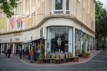 Eckstein, Recklinghausen Eckstein Café an einer Straßenecke mit Sitzgelegenheiten im Freien und Menschen, die vorbeigehen.