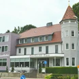 Hotel Felsenkeller_Bad Iburg_Teutoburger Wald Tourismus_I Bohlken (3)_3000.jpg Außenansicht eines mehrstöckigen Hotels mit Türmchen, Waldbewuchs im Hintergrund, Fassade in Weiß-Grau.