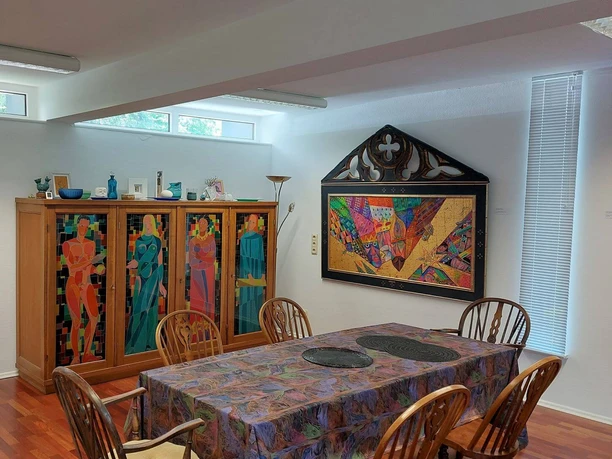 Museum Raffael Becker A colorful exhibition space with vibrant artwork and a furnished table.