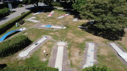 Minigolfplatz am Unterbacher See nahe Erkrath / Düsseldorf Minigolfplatz mit verschiedenen Bahnen auf einer Grünfläche, umgeben von Bäumen und Sträuchern.