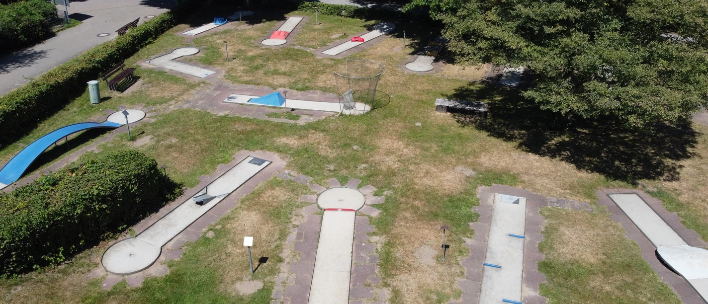 Minigolfplatz am Unterbacher See nahe Erkrath / Düsseldorf Minigolfplatz mit verschiedenen Bahnen auf einer Grünfläche, umgeben von Bäumen und Sträuchern.