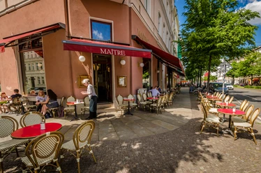Café Maître - Cafés in Leipzig Blick auf den sonnigen Freisitz des Café Maître mit roten Tischdecken an der Karl-Liebknecht-Straße, freizeit, kaffeehaus, gastronomie
