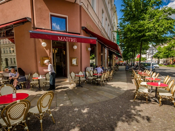 Café Maître - kavárny v Lipsku Pohled na prosluněné venkovní posezení kavárny Café Maître s červenými ubrusy na ulici Karl-Liebknecht-Straße, volný čas, kavárna, gastronomie
