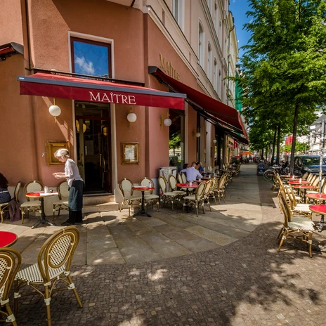 Widok na słoneczną zewnętrzną część wypoczynkową Café Maître z czerwonymi obrusami na Karl-Liebknecht-Straße, rozrywka, kawiarnia, gastronomia