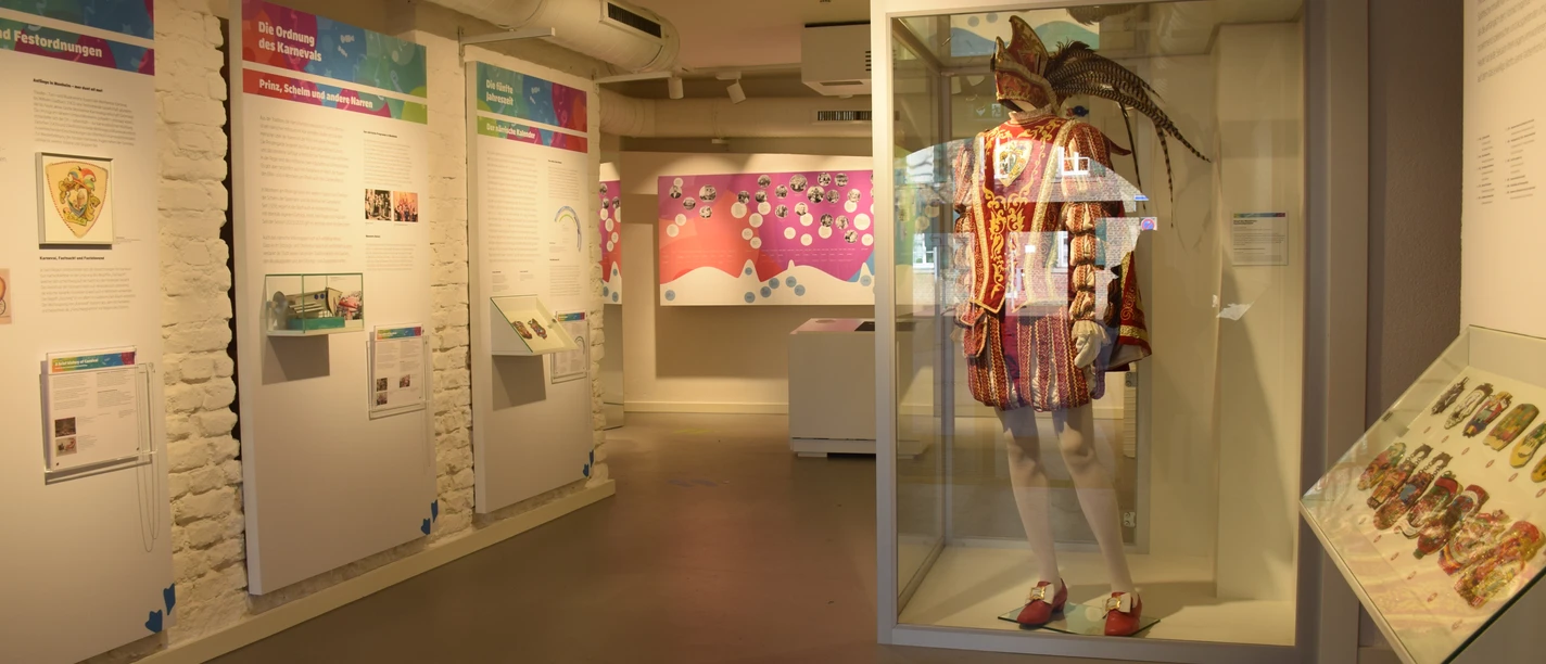 Karnevalskabinett in Monheim am Rhein Exponate im Karnevalsmuseum Monheim: bunte Schautafeln und ein prächtiges Kostüm in Vitrine.