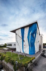 Bergstation Hilden Kletterhalle in modernem Design, großes Gebäude mit blauer und weißer Fassade, Parkplätze nahebei.