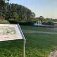 Rheinbogen mit Wasserspielplatz in Monheim am Rhein Freizeitfläche mit Spielplatz in grüner Umgebung am Rhein, Spielgeräte und Besucher im Hintergrund.